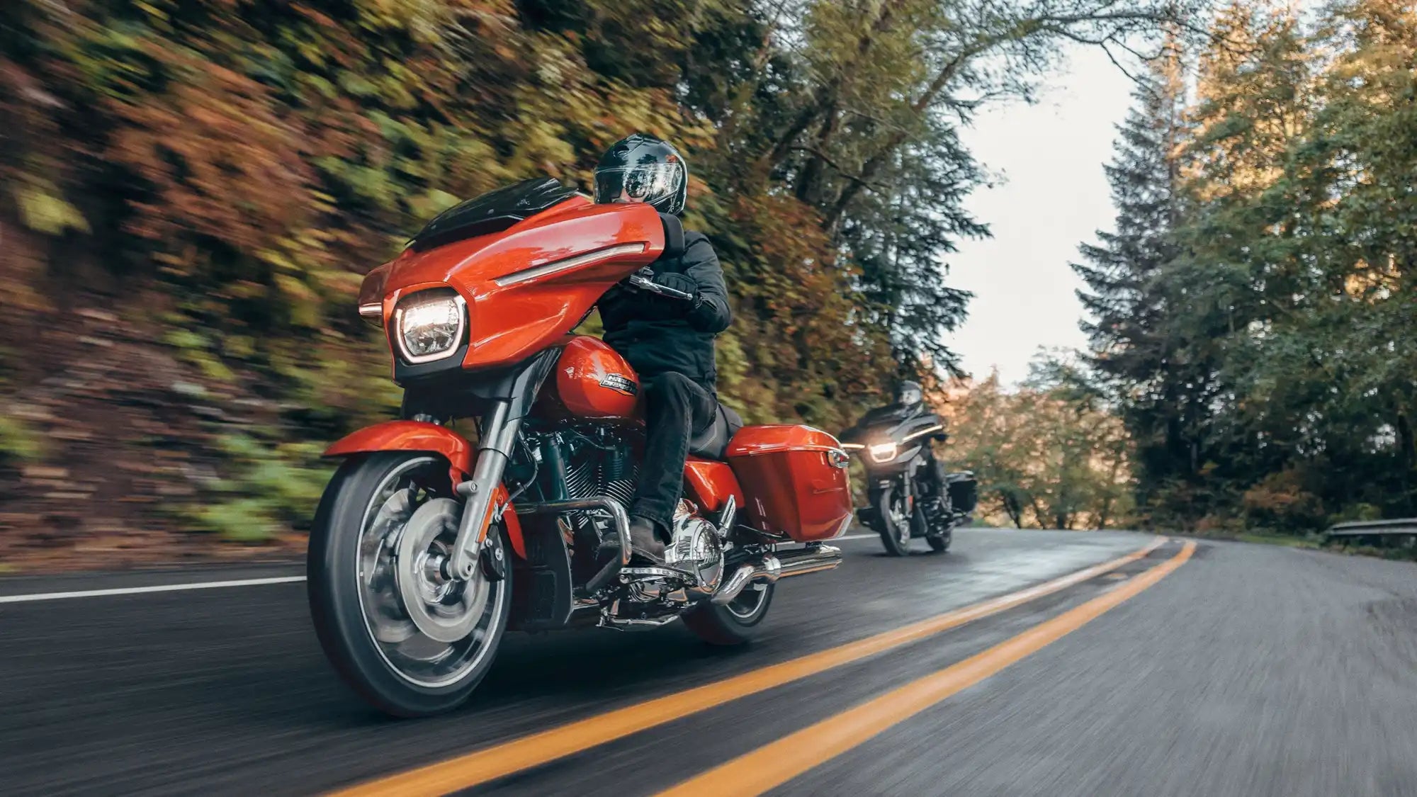 Red touring motorcycle with a front fairing and saddlebags cruising on a road.